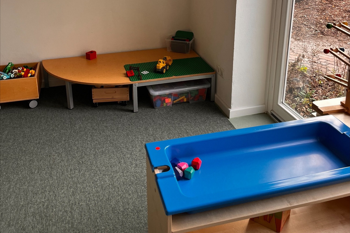 Ein heller Raum mit Teppichboden, ausgestattet mit verschiedenen Spielzeugen.