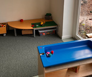 Ein heller Raum mit Teppichboden, ausgestattet mit verschiedenen Spielzeugen.