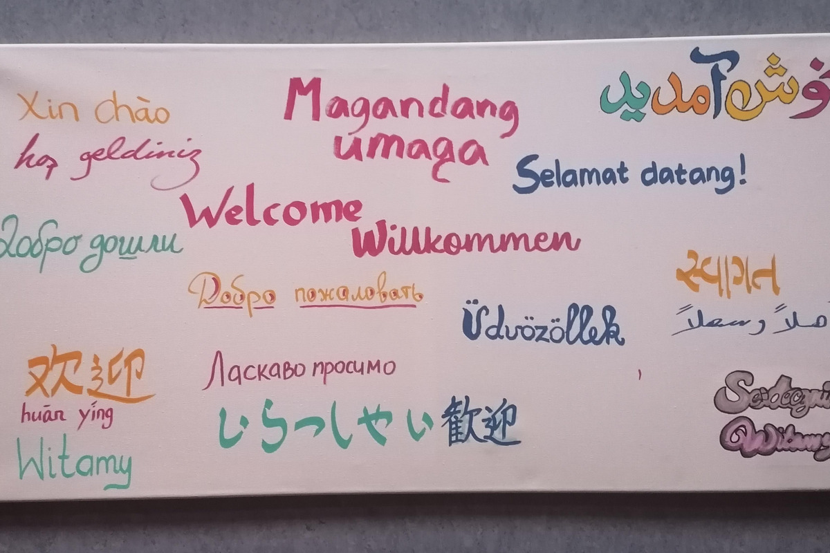 Das Bild zeigt verschiedene Begrüßungen in mehreren Sprachen. 