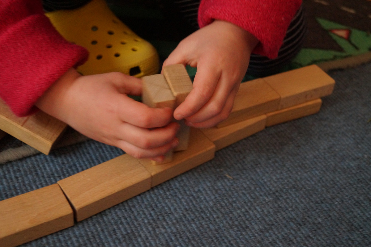 Ein Kind baut mit Holzbausteinen.