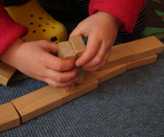 Ein Kind baut mit Holzbausteinen.