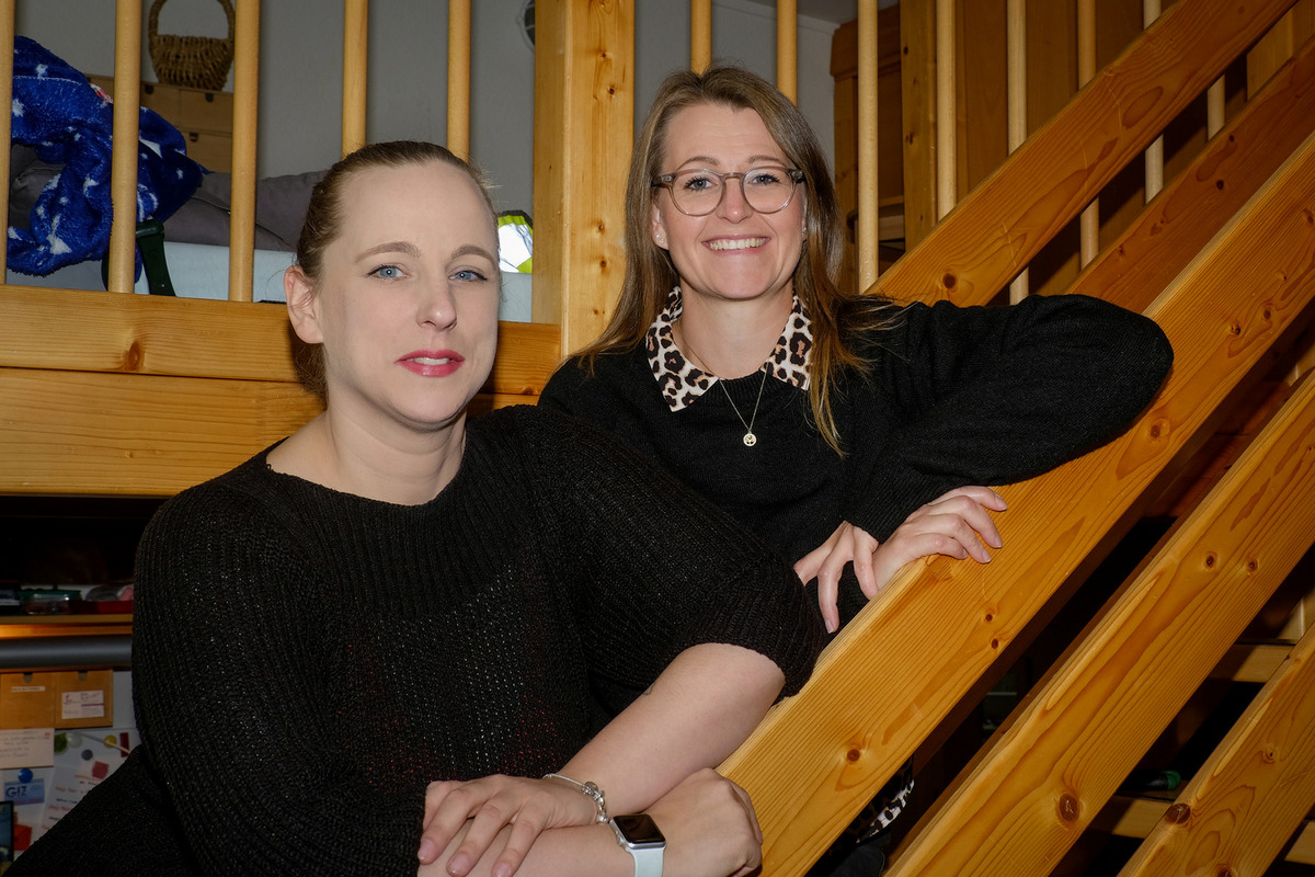 Zwei Frauen stehen an einer Holztreppe. 