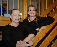 Zwei Frauen stehen an einer Holztreppe. 