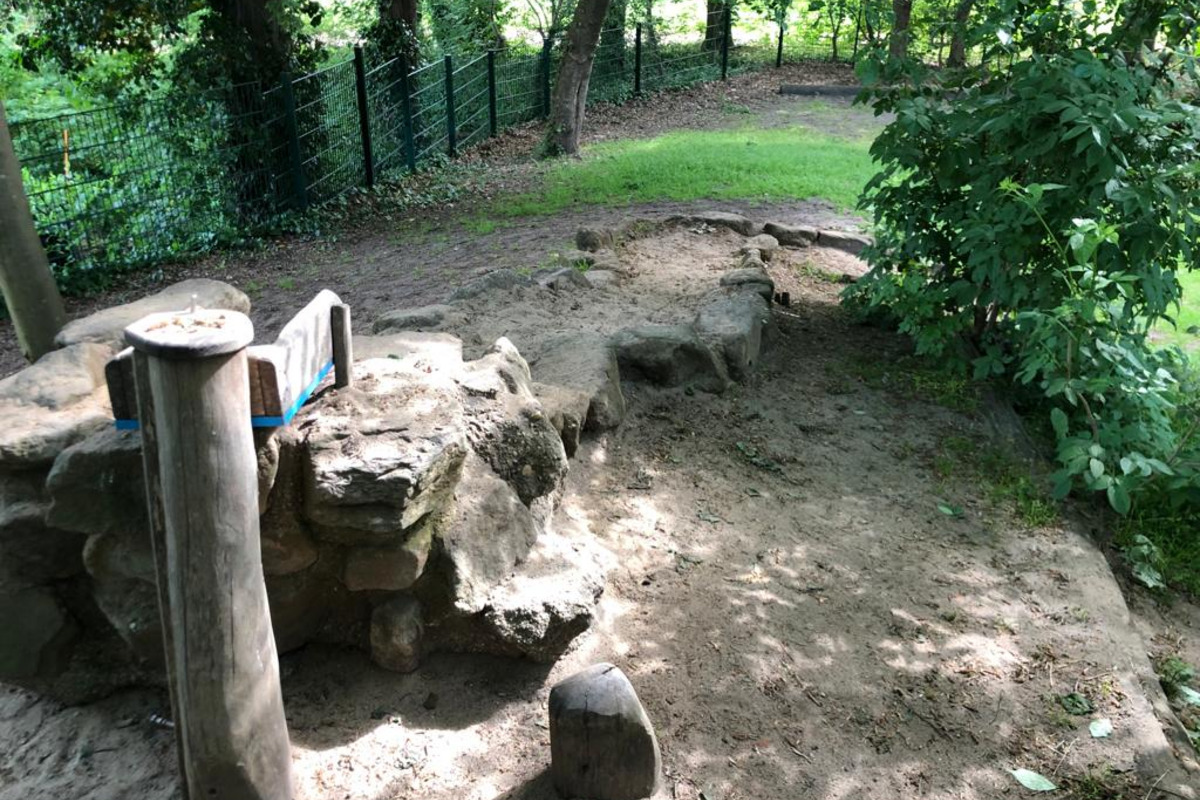 Ein schmaler, ungeteilter Pfad aus Erde und Sand führt über unregelmäßige Steine. 
