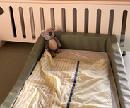 Ein Kinderbett mit einer grünen Umrandung steht im Vordergrund. 