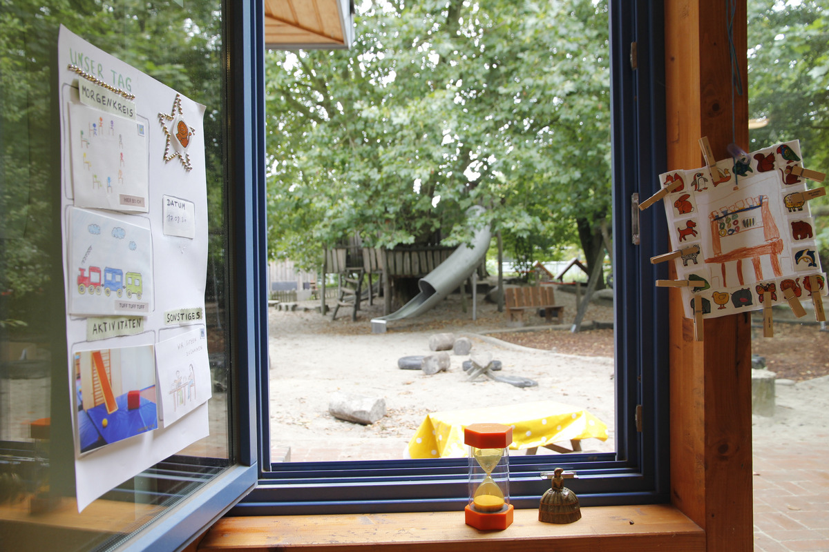 Blick aus einem Fenster auf einen Kindergartenbereich mit Spielgeräten. 