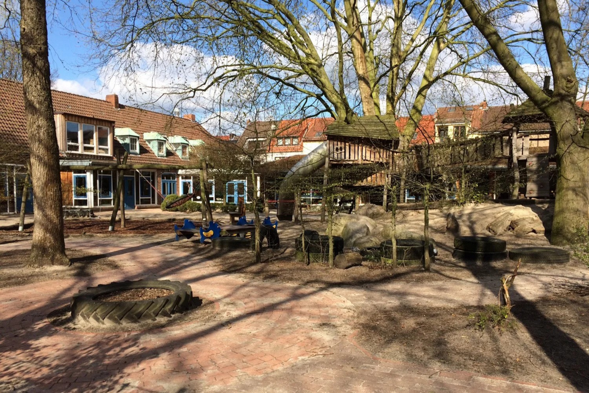 Ein Spielplatz mit verschiedenen Spielgeräten, darunter eine Rutsche und ein Klettergerüst.