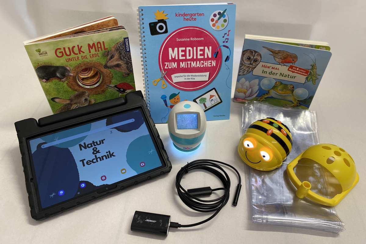 Die Abbildung zeigt eine Sammlung von Lernmaterialien für Kinder. Darunter befinden sich Bücher über Natur und Technik, ein Tablet mit einer thematischen Bildschirmdarstellung, ein Endoskop sowie Zubehörteile für kreative Aktivitäten.