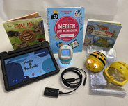 Die Abbildung zeigt eine Sammlung von Lernmaterialien für Kinder. Darunter befinden sich Bücher über Natur und Technik, ein Tablet mit einer thematischen Bildschirmdarstellung, ein Endoskop sowie Zubehörteile für kreative Aktivitäten.
