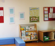 Der Raum zeigt eine Bücherwand mit einer Vielzahl von Kinderbüchern. An der Wand hängen Informationsblätter und ein Plakat mit dem Titel „Kinder haben Rechte!“, das wichtige Rechte von Kindern hervorhebt. Ein blauer Sitzbereich ergänzt die Einrichtung.
