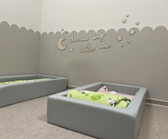 Ein gemütlicher Raum mit zwei grauen Betten, die mit bunten Decken ausgestattet sind. An der Wand steht der Schriftzug „dream big little one“ über einer dekorativen Halbmond- und Sternenmotivik.