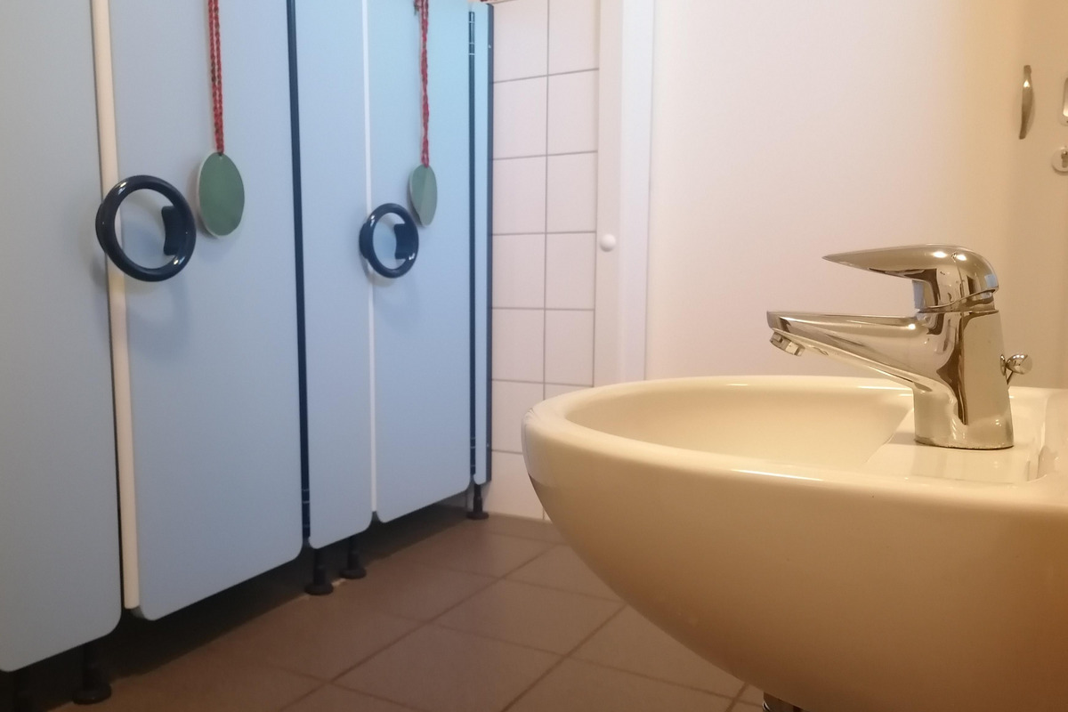 Ein Waschbecken mit einem glänzenden Wasserhahn steht im Vordergrund.