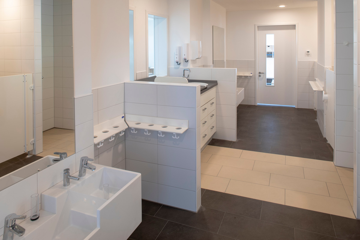 Das Bild zeigt ein modernes Badezimmer mit weißen Fliesen und einem großen Spiegel.