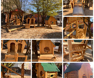 Das Bild zeigt einen Spielplatz mit Holzspielgeräten, darunter mehrere kleine Spielhäuser, Rutschen und Kletterelemente. 