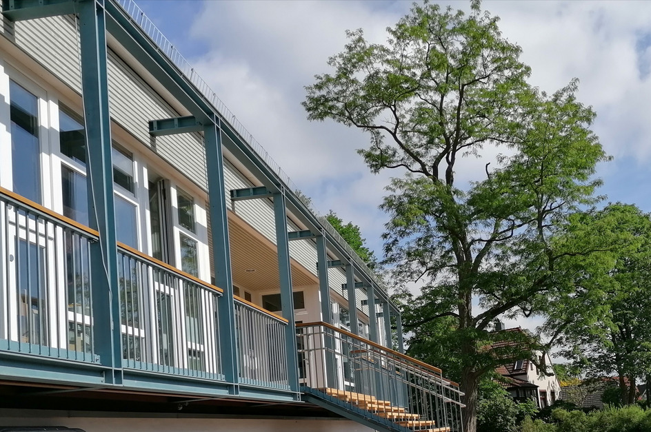 Ein modernes Gebäude mit Balkon und großen Fenstern. 