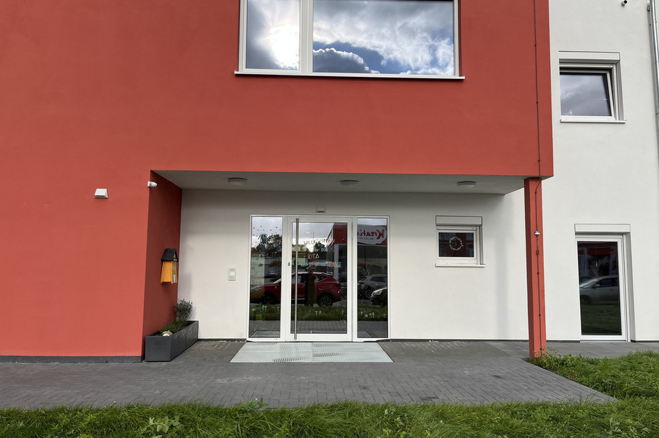 Der Eingang zu einem modernen Gebäude, das hauptsächlich in Rot und Weiß gestrichen ist.