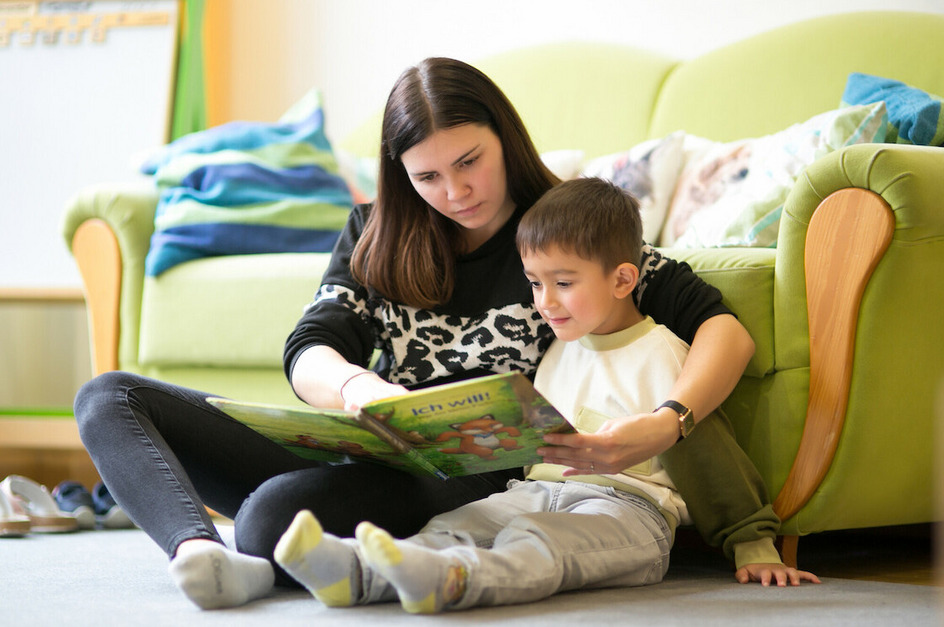Mitarbeiterin schaut sich zusammen mit einem Kind ein Buch an