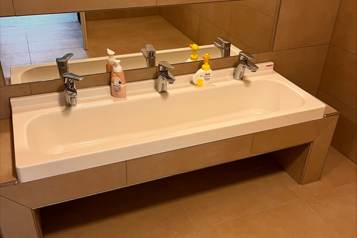 Ein modernes Badezimmer mit einem schlichten, langen Waschbecken für Kinder