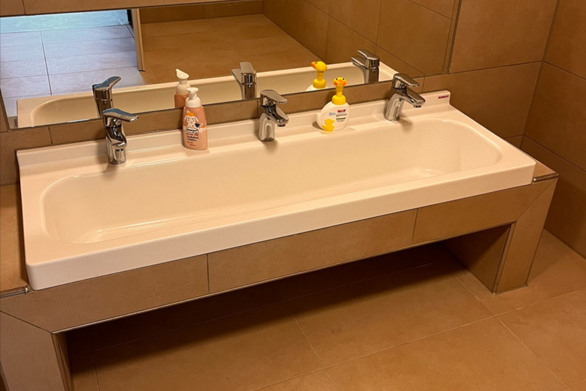 Ein modernes Badezimmer mit einem schlichten, langen Waschbecken für Kinder