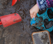 Zwei Hände graben im nassen Sand. 