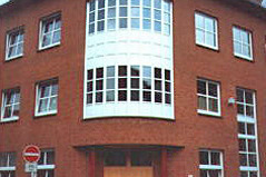 Das Bild zeigt ein rotes Gebäude mit einer markanten, runden Vorderseite. 