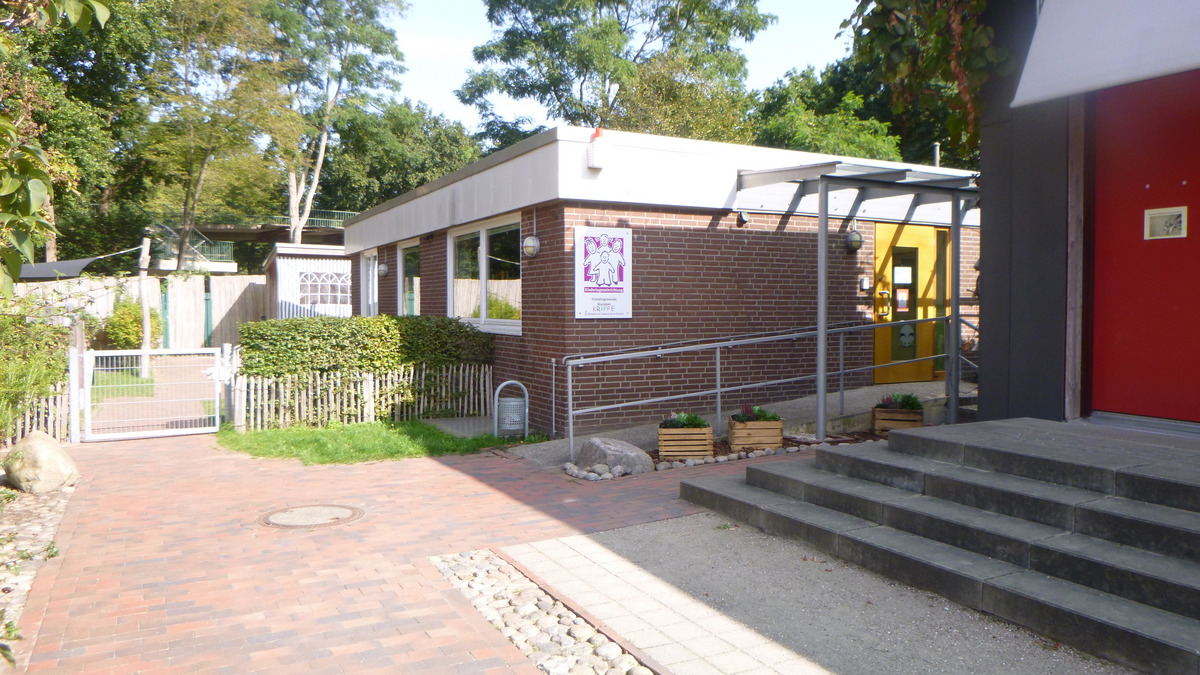 Ein eingeschränktes, modernes Gebäude mit rot gefärbtem Eingang und gelber Tür. Auf der Fassade befindet sich ein buntes Schild mit einem Logo. 