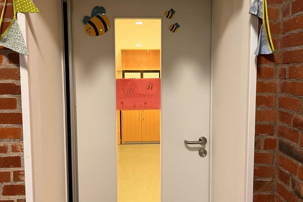 Die Eingangstür ist geschmückt mit einer bunten Girlande und kleinen Bienen. 