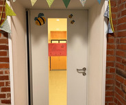 Die Eingangstür ist geschmückt mit einer bunten Girlande und kleinen Bienen. 