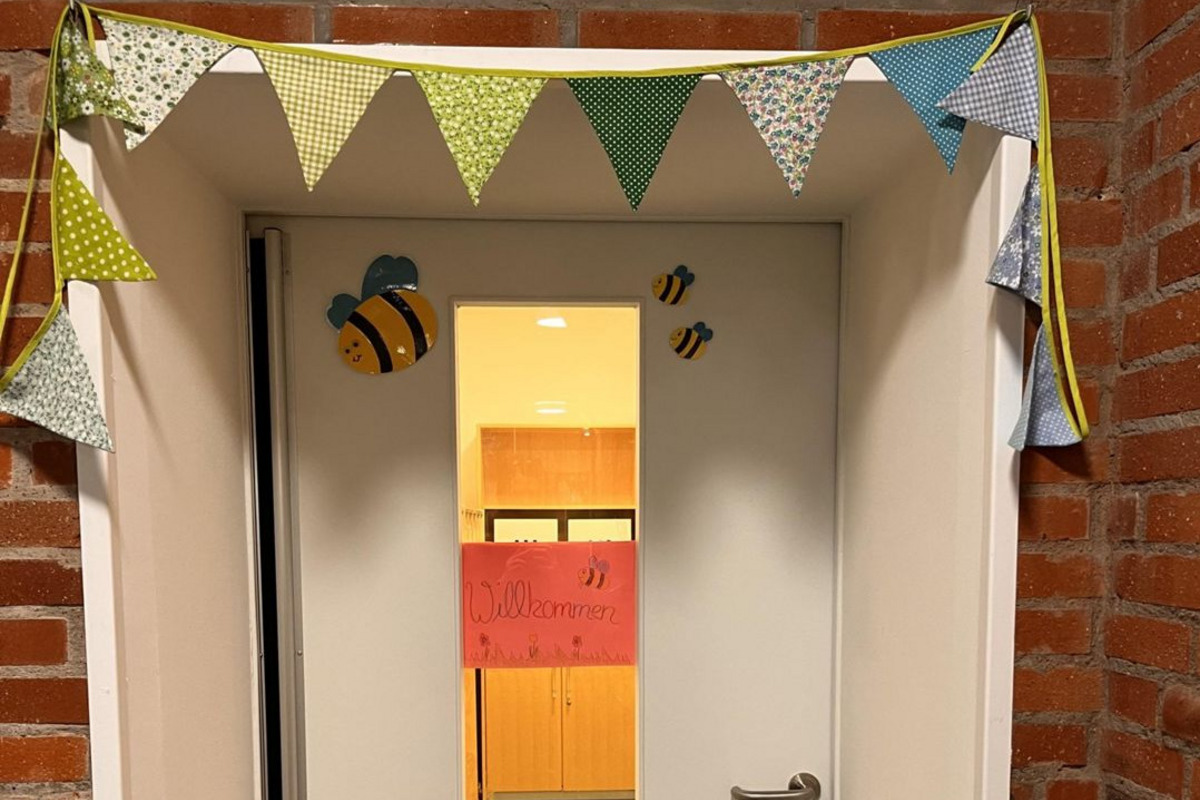 Die Eingangstür ist geschmückt mit einer bunten Girlande und kleinen Bienen. 