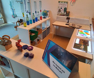 Ein heller Raum mit verschiedenen Tischen, auf denen wissenschaftliche Materialien und Experimente präsentiert werden. 