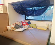 Ein gemütlicher, gepolsterter Bereich mit verschiedenen Kissen liegt unter einem Fenster. 