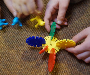 Die Hände von Kindern halten bunte Spielzeugteile. 