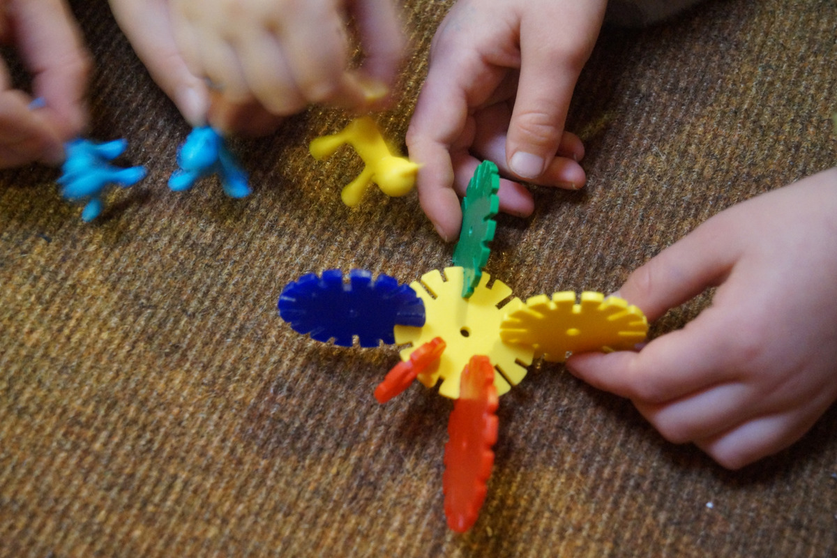 Die Hände von Kindern halten bunte Spielzeugteile. 